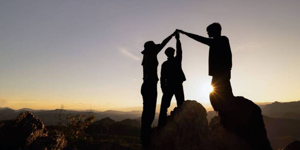 silhouettes of three people holding hands 
